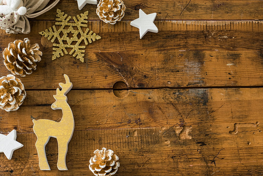Christmas decorations, rustic wooden planks, vintage flatlay, seasonal themes, brown conifer cones, wooden surface, Christmas ornaments, festive decor, holiday theme, rustic Christmas, wooden deer ornament