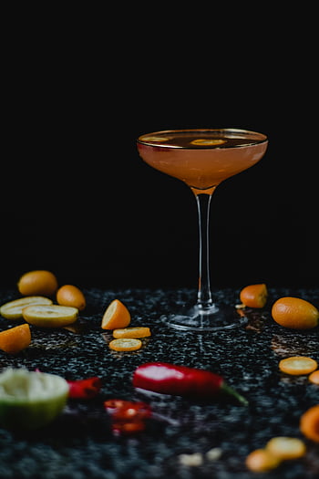 kumquat cocktail, orange liquid, clear cocktail glass, dark marble, fresh fruits, food photography, drink photography, elegant drink, cocktail garnish, fruit garnish, cocktail presentation