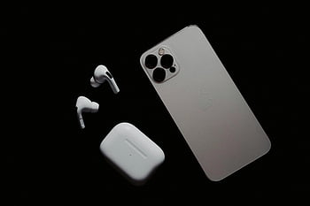 iPhone, AirPods, smartphone, wireless earbuds, modern tech, dark surface, close-up, gadgets, Apple products, tech accessories, tech devices