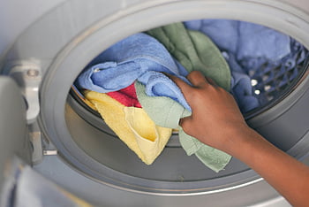 woman hand, loading towels, washing machine, front-loading, colorful towels, laundry, close-up, household chores, cleaning, domestic tasks, appliance