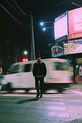 uomo che cammina, Attraversamento pedonale, attraversamento pedonale trafficato, paesaggio urbano vibrante, scena notturna, strada urbana, luci della città, fotografia notturna, fotografia di strada, uomo in pausa, vita notturna della città