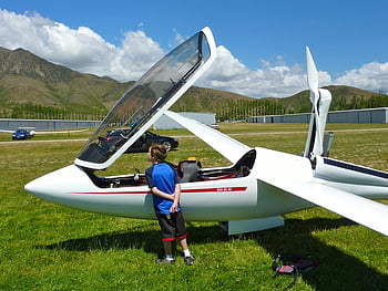 child, white glider, airfield, sunny day, curious child, sleek white glider, outdoor activity, aviation interest, young explorer, airplane examination, open cockpit