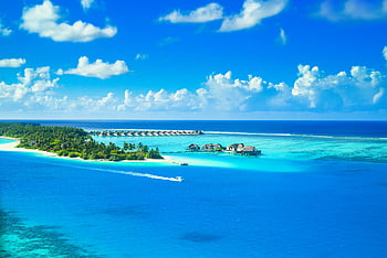 Maldives Island, aerial view, luxurious tropical resort, pristine island, azure waters, lush greenery, overwater bungalows, tropical paradise, blue lagoon, white sand beach, speedboat