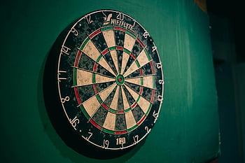 worn dartboard, green wall, indoor sports, entertainment themes, dart game, recreational activities, sports equipment, wall-mounted dartboard, vintage dartboard, sports decor, indoor games