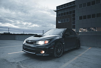 black Subaru Impreza, urban parking lot, overcast sky, dusk, black car, Subaru, Impreza, parking lot, urban setting, overcast, dusk lighting