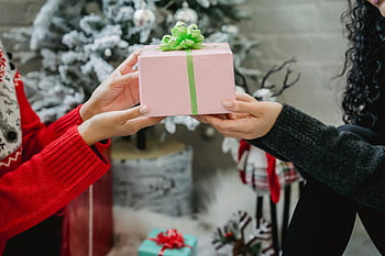 Julklappbyte, Kvinnlig gåva, festlig atmosfär, dekorerade julgran, Två kvinnor som utbyter gåvor, jullov, presentlåda, varm semesterscen, semestergåva, julklappar, storhelg