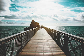 people walking, wooden dock, Biarritz France, ocean view, travel inspiration, stunning bridge, seaside walkway, coastal scenery, outdoor activity, scenic path, travel destination
