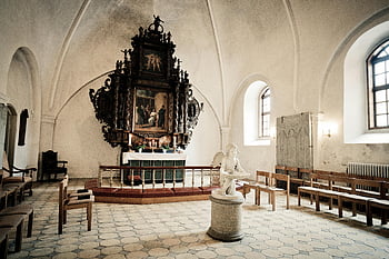 estatua de anjo, Interior da capela, igreja histórica, altar proeminente, arquitetura clássica, arte religiosa, estatua de pedra, janelas arqueadas, bancos de madeira, iconografia religiosa, design de interiores