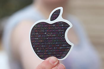 apple-shaped sticker, binary code, technology symbol, close-up photo, person holding, black sticker, coding, programming, tech symbol, digital art, sticker design