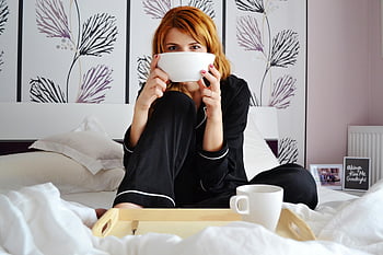 ผู้หญิงในชุดนอน, นั่งบนเตียง, ถือชาม, ห้องนอนที่สะดวกสบาย, กาแฟหนึ่งแก้ว, ห้องนอนที่มีสไตล์, การผ่อนคลาย, เช้าประจำวัน, เตียงนอนสบาย, อาหารเช้าบนเตียง, เช้าวันใหม่