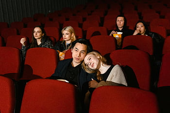 Guardando film, coppie nel cinema, Accogliente cornice cinematografica, temi di intrattenimento, Persone che guardano il film, sedili cinematografici rossi, Night del film di gruppo, esperienza cinematografica, pubblico cinematografico, Cinema romantico, Night cinematografica accogliente