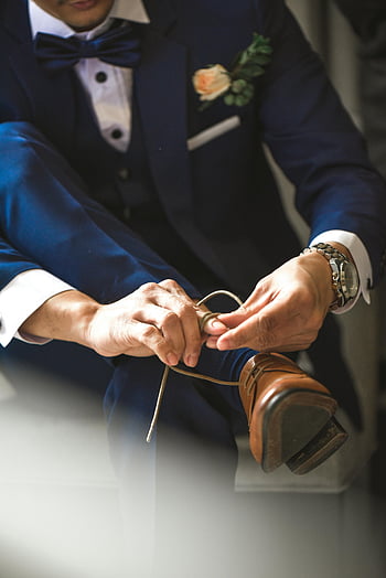 Muž vázání tkanic, oblek, hnědé kožené boty, detail, uvnitř, formální oblečení, motýlek, boutonniere, náramkové hodinky, elegantní, příprava