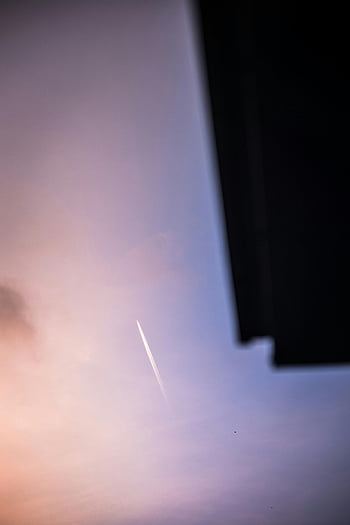 airplane contrails, pastel sky, sunset scene, tranquil atmosphere, sky streaks, evening sky, soft colors, aviation trails, peaceful sky, contrail photography, sunset contrails