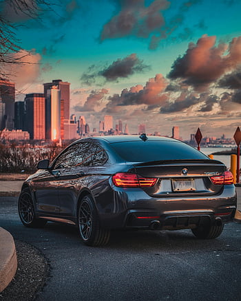 Black BMW M3 Coupe, city skyline, sunset, urban luxury, lifestyle, sleek coupe, parked car, stunning backdrop, BMW coupe, road, skyline backdrop