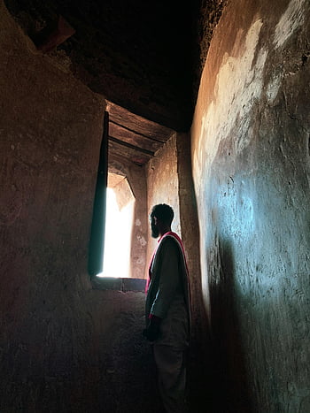 man, looking out window, abandoned building, ancient building, gazing out window, deep in thought, window view, interior shot, contemplative man, rustic architecture, natural light