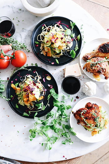 colorful gourmet dishes, fresh vegetables, herbs, white tabletop, variety of food dishes, roasted chicken, pasta, tomatoes, wine, garlic, decorative herbs