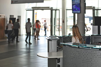office reception, bustling office, modern desk, receptionist, people walking, counter, television, office area, modern office, reception area, white sitting