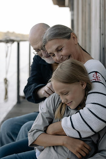 grandparents, granddaughter, family time, outdoor setting, loving embrace, serene day, multi-generation family, grandparents and grandchild, affectionate moment, family bonding, outdoor family photo