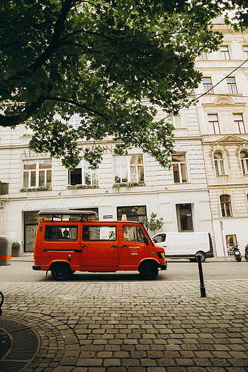 red van, Vienna, Austria, charming street, vibrant red, parked van, lush tree, city scene, urban setting, European city, cobblestone street