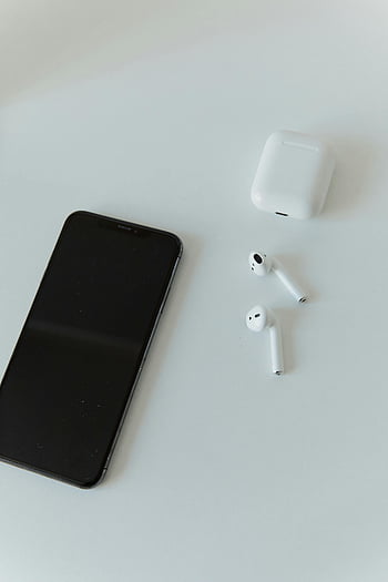 Black iPhone, Airpods, white table, modern smartphone, wireless earphones, minimalist design, contemporary technology, tech gadgets, Apple products, sleek design, tech accessories