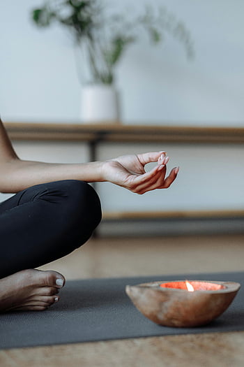 yoga mudra, close-up shot, hand pose, lit candle, tranquility, meditation, yoga practice, relaxation, spiritual practice, indoor setting, peaceful atmosphere