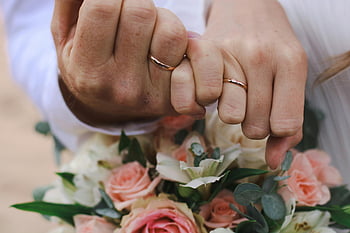 wedding rings, couple hands, close-up photo, love and commitment, intimate moment, floral bouquet, romantic image, wedding day, ring details, hand holding, couple unity