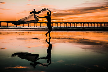 sunset beach, silhouette photo, person holding scarf, graceful figure, dancing with scarf, stunning silhouette, beach reflection, sunset silhouette, beach dance, sunset dance, beach sunset