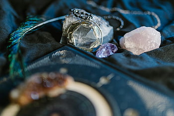 spiritual rituals, gemstones, crystals, blue textile, silver ring, gold ring, delicate display, amethyst, quartz, peacock feather, jewelry