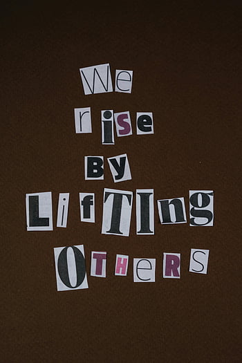 paper cutouts, brown surface, inspirational quote, we rise by lifting others, motivational text, cutout letters, brown backdrop, inspirational message, paper art, uplifting quote, paper collage