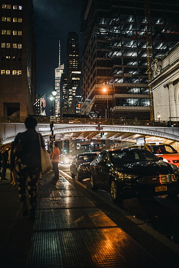 woman walking, street, running vehicle, dynamic city, night, vibrant lights, traffic, skyscrapers, Grand Central Terminal, Square Plaza, urban scene
