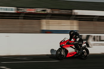 motorkerékpár versenyző, fekete sisak, dinamikus lövés, gyors tempójú akció, motorsport, versenypálya, sebesség, motorkerékpár, sportfotózás, akció lövés