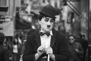 black and white photo, man in suit, bowler hat, street performer, classic silent film, Charlie Chaplin, black and white, street performance, classic character, black and white photography