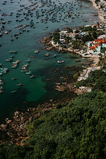 aerial shot, coastal village, Vietnam, colorful rooftops, numerous boats, watercrafts docked, vibrant coast, tropical scenery, seaside community, fishing boats, rocky shoreline