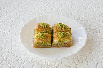 baklava, Turecký dezert, pistácie, bílá deska, detailní záběr, Dezertní nadšenci, chutná baklava, bílá keramická deska, Descert detect, Turecká baklava, pistáciová poleva