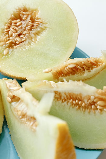 honeydew melon, sliced fruit, close-up photo, juicy honeydew, melon slices, seeds, blue plate, fresh fruit, healthy food, fruit photography, melon seeds