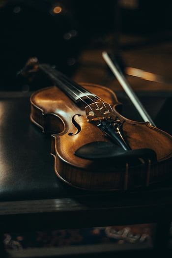 brown violin, fiddlestick, close-up, leather chair, bow, moody lighting, musical instrument, string instrument, classical music, dark background, artistic photography