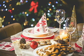 Christmas table, festive lights, clear long stem drinking glass, holiday decorations, Christmas food, Christmas ornaments, Christmas napkins, Christmas tree, festive table setting, holiday dinner, Christmas party