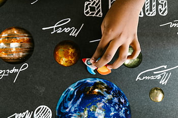 handmade planets, child's hand, model planets, space-themed board, educational board, space learning, planet models, child education, space toys, astronomy learning, space-themed toys