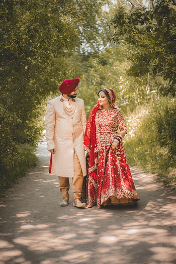 Zuid -Aziatische bruiloft, bruid in rode lehenga, bruidegom in kurta, traditionele kleding, buitenpad, prachtig uitzicht, paar wandelen, Indiase bruiloft, culturele kleding, romantische scène, natuur achtergrond
