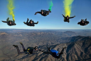 skydivers, colorful smoke trails, mountainous terrain, aerial shot, dynamic performance, stunts, parachuters, air, extreme sports, adventure, outdoor activities