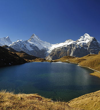 alpine landscape, tranquil blue lake, snowy mountains, clear sky, majestic view, mountain reflection, serene nature, high altitude, natural beauty, outdoor scenery, alpine lake
