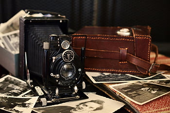 černá skládací kamera, hnědá kožená taška, fotografie ve stupních šedi, vinobraní fotoaparát, Nostalgické kouzlo, staré fotografie, klasický fotoaparát, kožené pouzdro, retro fotografie, starožitný fotoaparát, Vintage Charm
