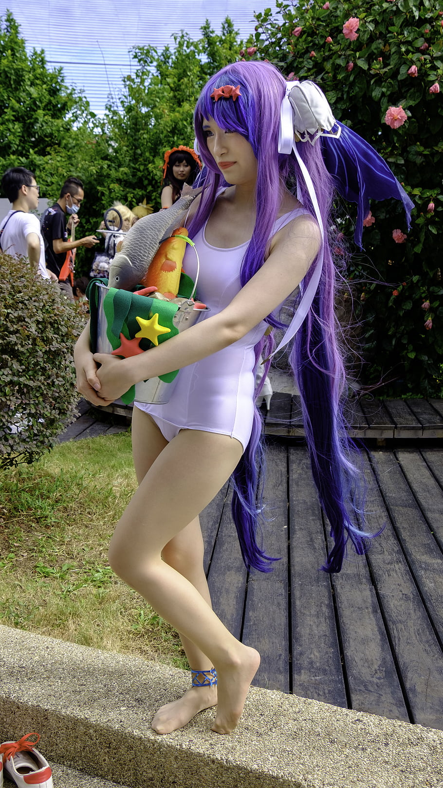 cosplay, purple hair, white swimsuit, fish bag, outdoor, wooden deck, green grass, people in background, flowers, ribbon, anime character