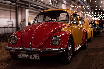 Vintage Volkswagen Beetle, close-up, red and yellow, indoor display, string lights, classic car, indoor event, automotive show, Volkswagen, Beetle, retro car