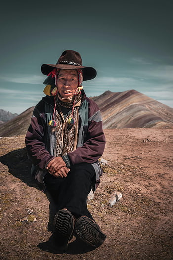 Peruvian elder, traditional clothing, Rainbow Mountain, Cusco, Peru, cultural landscape, desert setting, mountain backdrop, indigenous attire, cultural heritage, scenic view