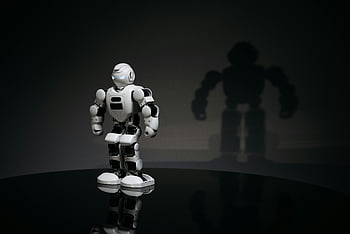 white robot toy, black surface, humanoid robot, studio setting, casting shadow, white and black toy, robot shadow, toy robot, studio photography, reflective surface, robot figure