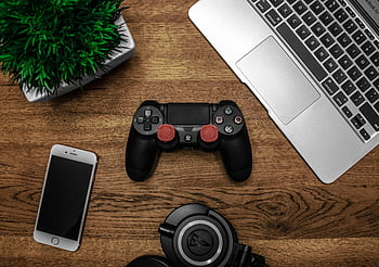 Black game console, wooden surface, flat lay, gaming console, laptop, smartphone, headphones, desk setup, tech gadgets, gaming accessories, office desk