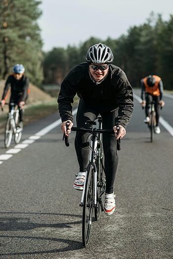 Muž v černé bundě, jízdní kolo, cyklisty, závody, otevřená venkovská cesta, Skupina cyklistů, Venkovní cyklistika, silniční cyklistika, cyklistická událost, sportovní aktivity, helma