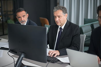 man using computer, office setting, business meeting, professionals working, modern office, computer work, business people, office environment, work at desk, corporate setting, business attire