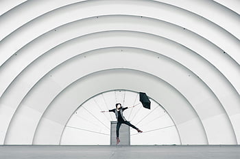 girl jumping, holding umbrella, large architectural arches, joyful jump, umbrella, white arches, person jumping, outdoor activity, dynamic pose, modern architecture, urban setting